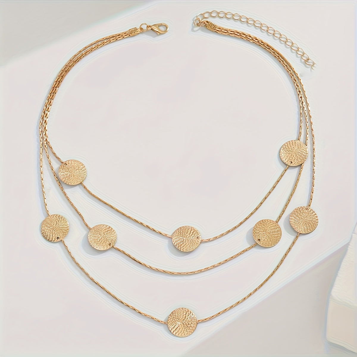 Geometrische goudkleurige gelaagde ketting met spiraalstructuur en meerdere schijven