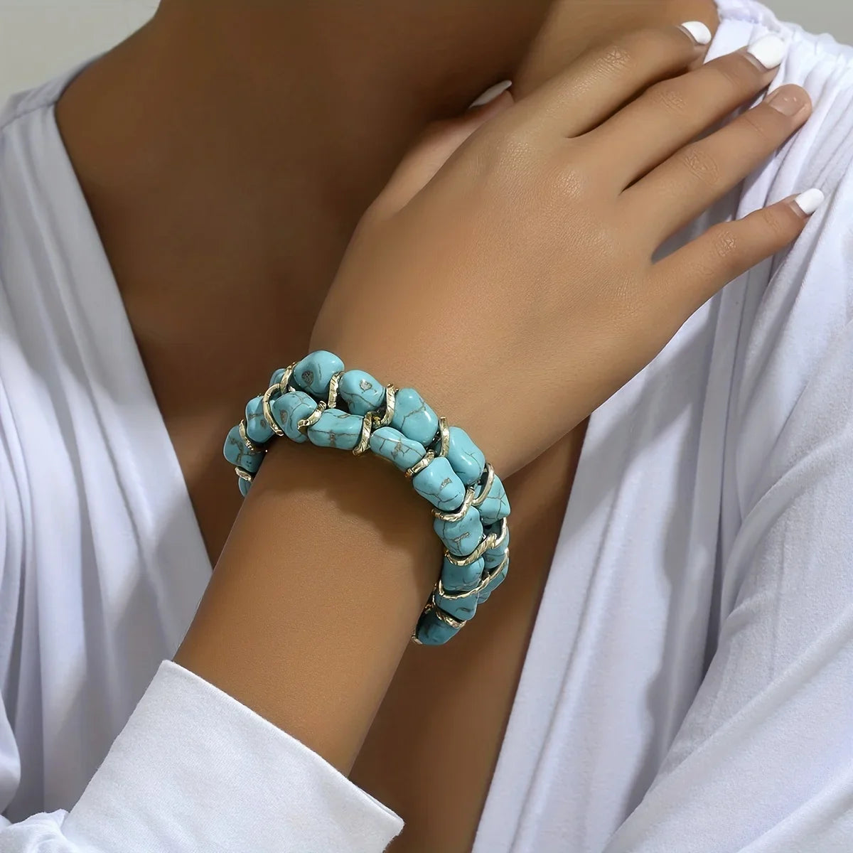 Gevlochten goudkleurige armband met turkooizen steen