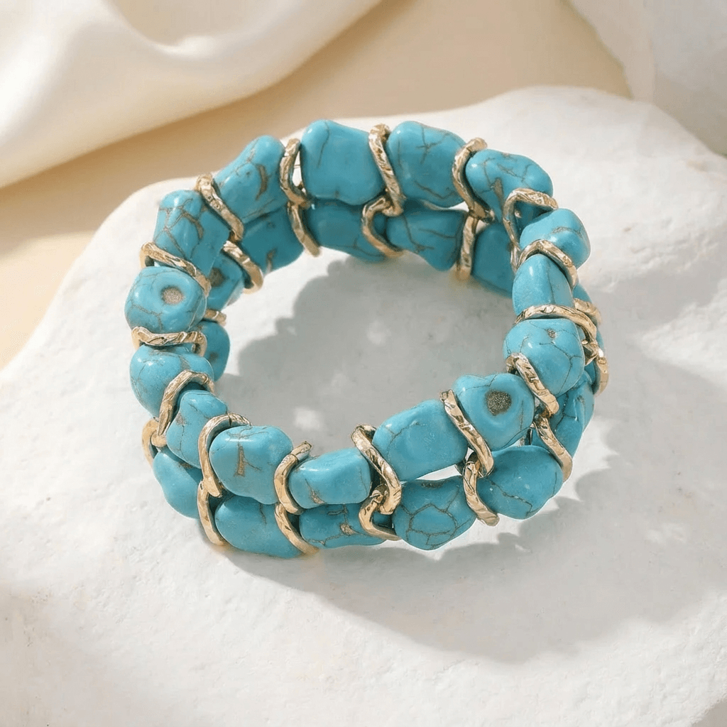 Gevlochten goudkleurige armband met turkooizen steen