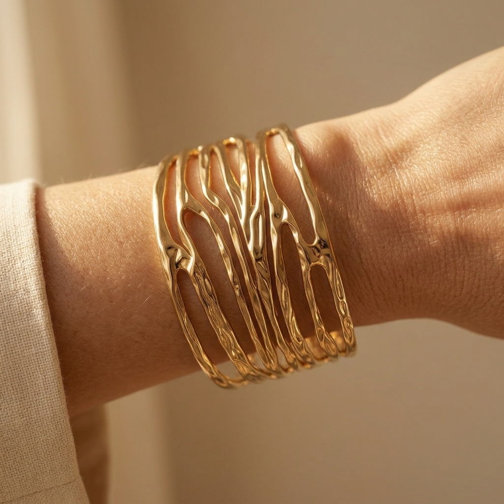 Goudkleurige cuff armband met structuur en opengewerkte golf